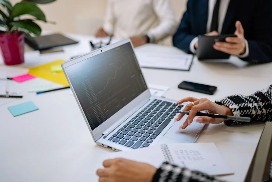 Hands typing on a laptop with cryptocurrency charts and smartphone display in view, focusing on digital finance.
